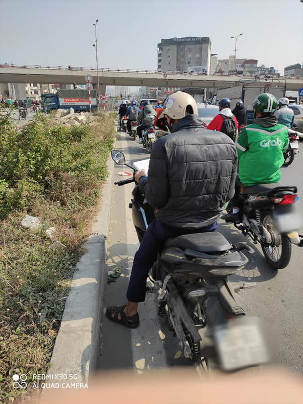 Đang dừng đèn đỏ nhưng chợt nhớ tới phải ôn bài, nam sinh mang sách vở ra học ngay giữa trời nắng - Ảnh 1.