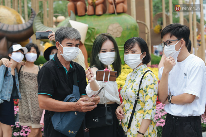 Ảnh: Người Sài Gòn xếp hàng đo thân nhiệt, đeo khẩu trang vào check in đường hoa Nguyễn Huệ - Ảnh 7.