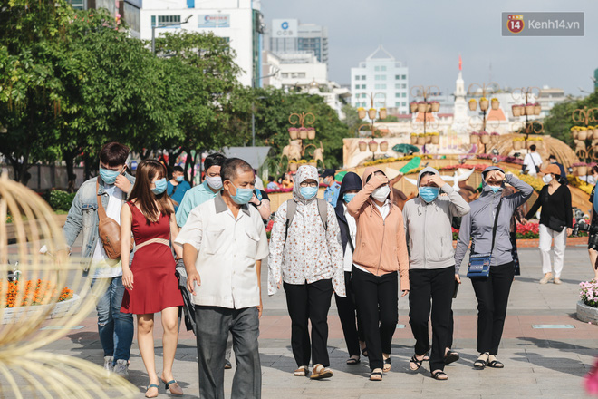 Ảnh: Người Sài Gòn xếp hàng đo thân nhiệt, đeo khẩu trang vào check in đường hoa Nguyễn Huệ - Ảnh 4.