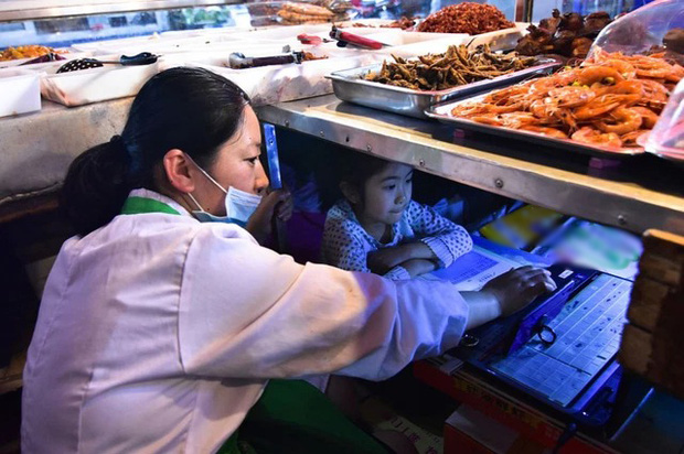 The photo of a baby studying under the stall of his mother selling at the market is causing great emotion: All for the hope of the future - Photo 3.