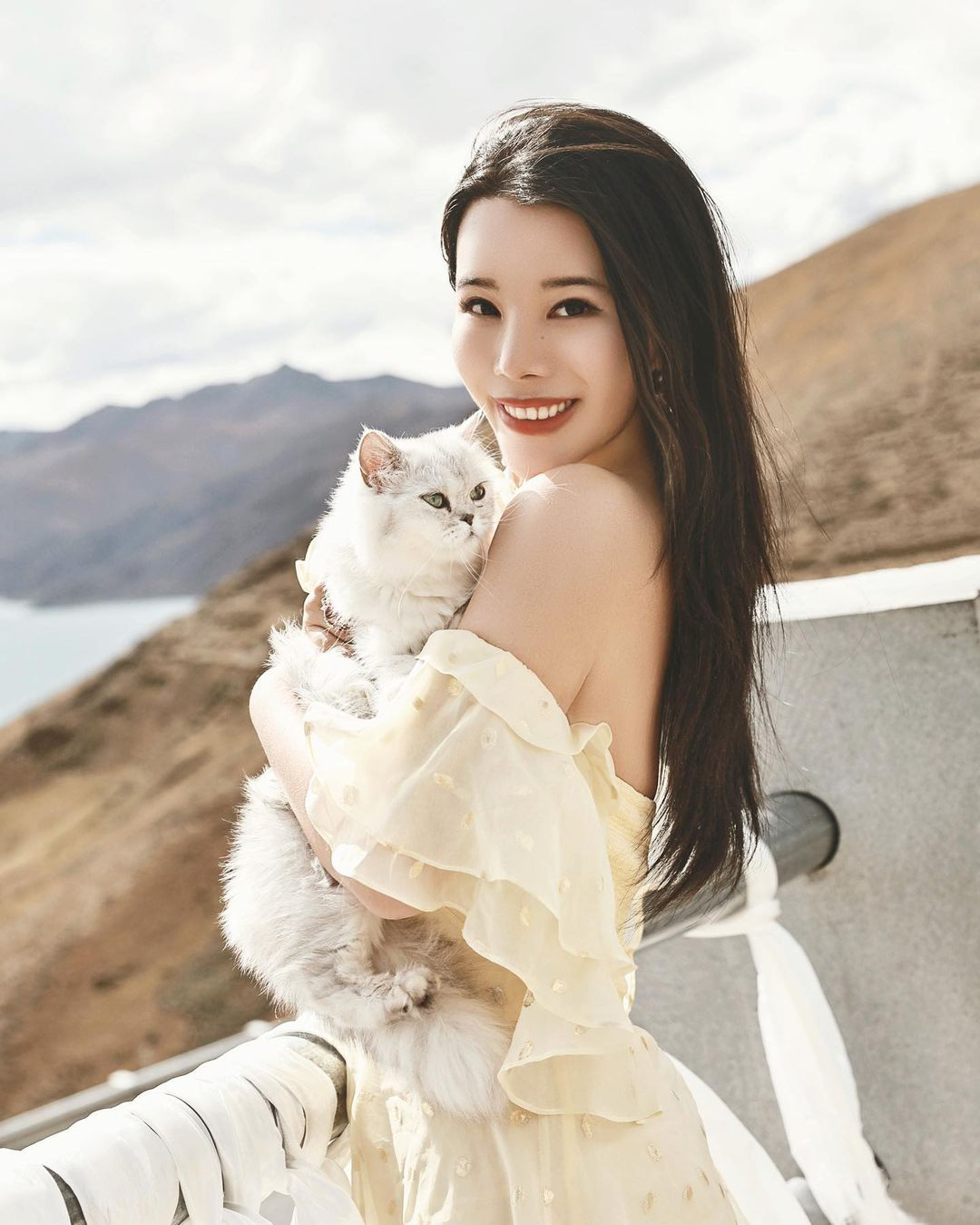 Chân Dung Người Phụ Nữ Trung Quốc Xinh Đẹp Trong Chiếc Váy Trắng Tạo Dáng  Với Nền Tường Trắng Cô Gái Trẻ Nhìn Và Mỉm Cười Trước Máy Ảnh Với Bàn Tay
