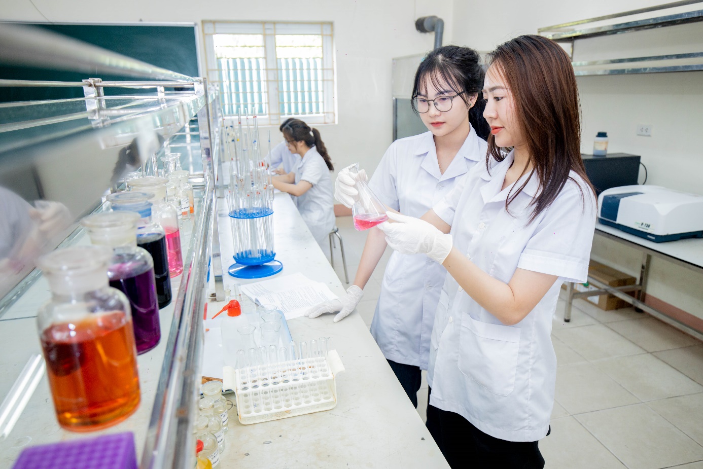 A group of women in lab coats in a laboratory Description automatically generated