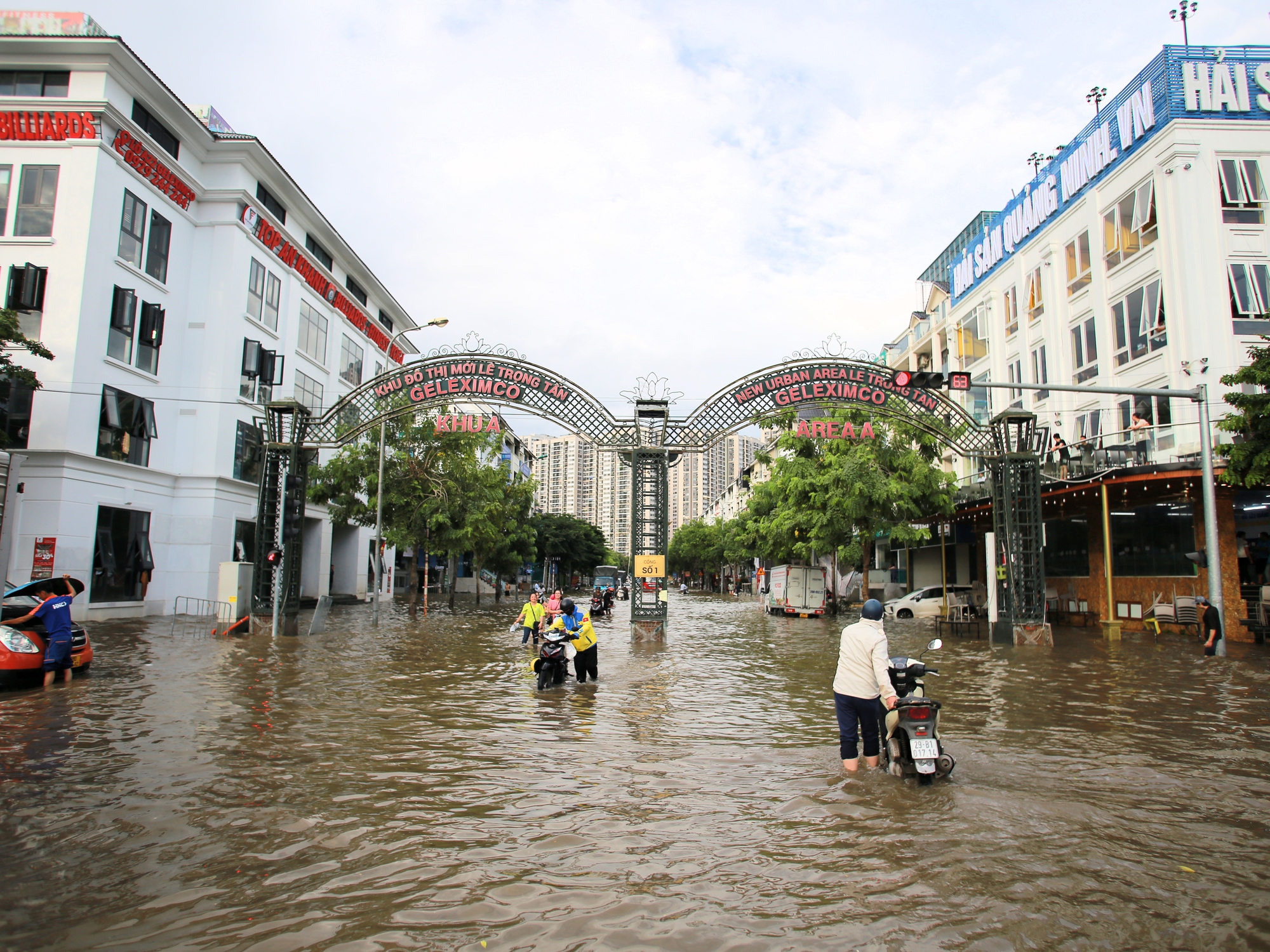 Trời hửng nắng, nhiều tuyến đường ở Hà Nội vẫn ngập sâu, người dân dùng tấm chắn để ngăn nước tràn vào nhà- Ảnh 2.