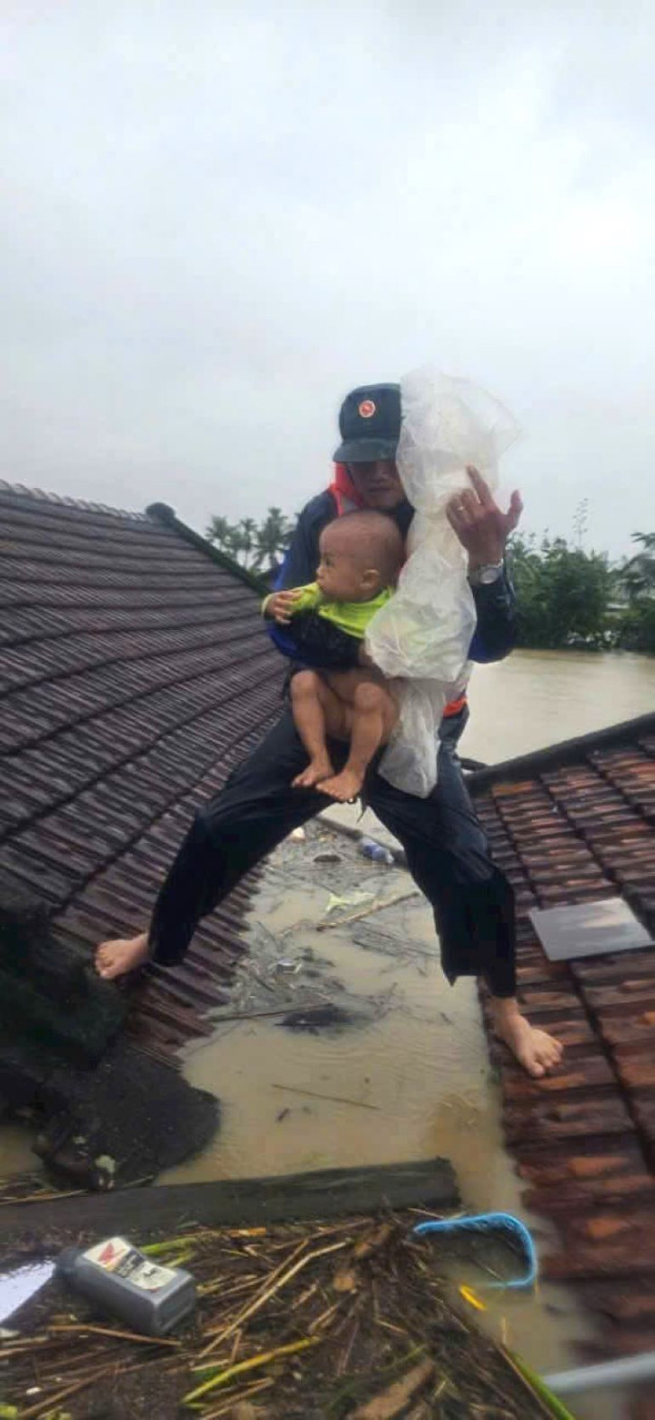 Thiếu tá Nguyễn Khắc Khiên bế em bé trên mái nhà giữa lũ dữ ở Đắk Lắk - Ảnh 1.