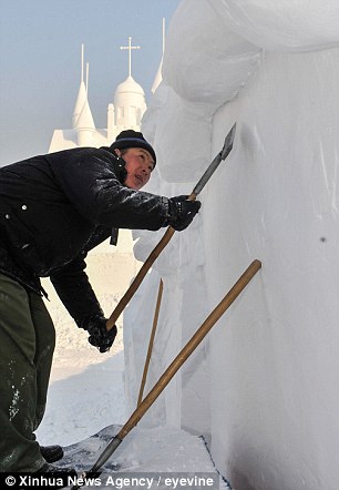 A worker shapes a snow sculpture at Jingyuetan National Forest Park in Changchun, capital of northeast China's Jilin Province