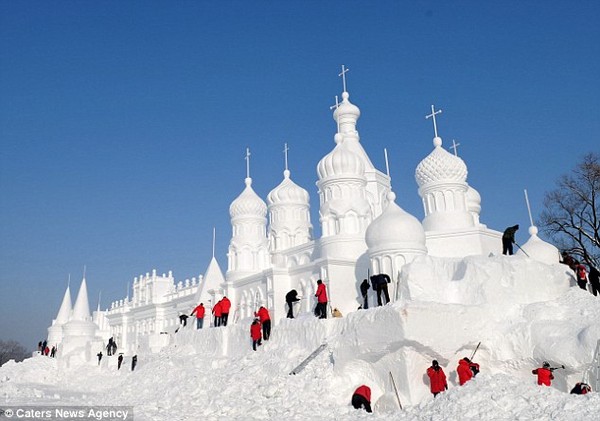 Teamwork: A group of workers beavers away as another stunning sculpture emerges from a heap of snow