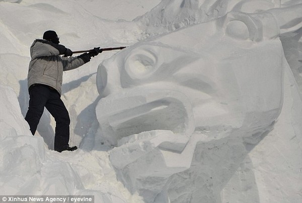 Final touches: A worker chisels away at the front of the horses sculpture to create the perfect effect