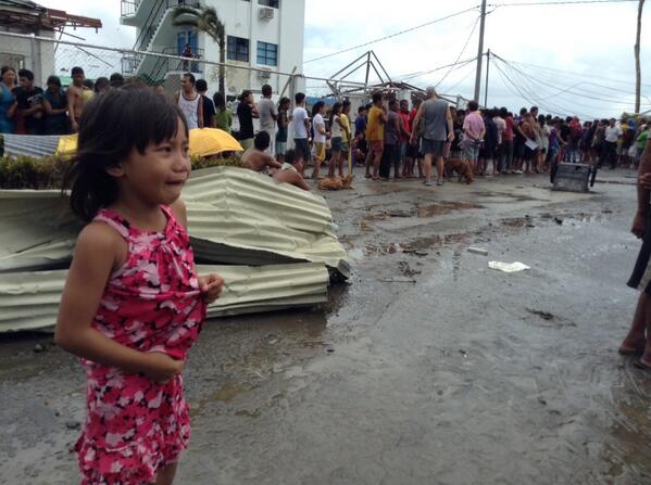 Một bé gái đứng khóc vì lạc mẹ trong khi đứng xếp hàng nhận thực phẩm cứu trợ...