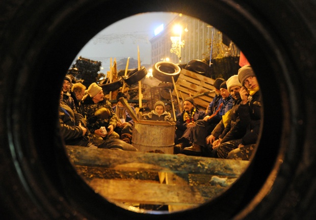 Người biểu tình ngồi sưởi ấm trong khi bảo vệ hàng rào trên quảng trường Độc lập ở Kiev, Ukraine.