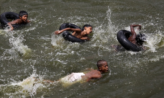 Trẻ em thi bơi với săm ô tô trên một hồ nước ở ngoại ô thủ đô New Delhi, Ấn Độ.