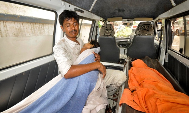 Người cha ôm đứa con gái tử vong trong xe cứu thương bên ngoài bệnh viện ở Patna, Ấn Độ. Bé gái cùng với 21 trẻ em khác đã tử vong do ăn bữa trưa miễn phí ghi chứa chất độc tại trường học.