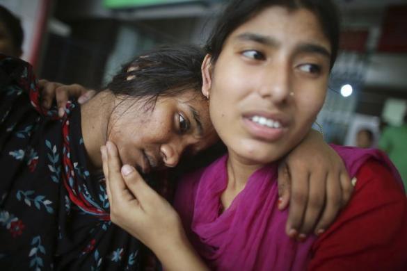 Một công nhân may giúp đưa đồng nghiệp tới bệnh viện sau khi bị thương trong khi tham gia biểu tình ở Dhaka, Bangladesh.