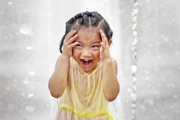 Bé gái thích thú chơi dưới trời nắng nóng trong một đài phun nước ở Thượng Hải, Trung Quốc.