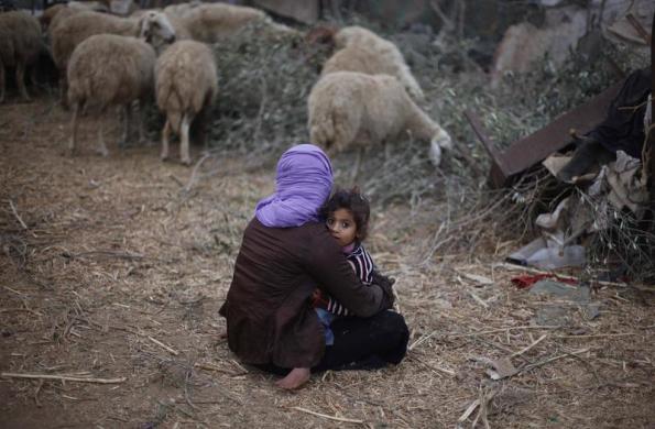 Một phụ nữ người Palestin ngồi bế con bên ngoài nhà ở al-Mugraga, Dải Gaza.