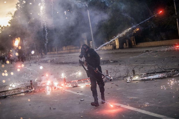 Một cảnh sát bạo động cúi đầu khi bị người biểu tình ném pháo sáng ở thủ đô Cairo, Ai Cập.