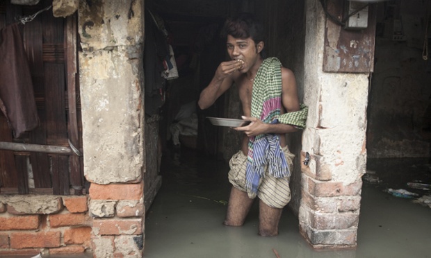 Một người đàn ông ăn trưa trong ngôi nhà ngập lụt ở miền bắc Ấn Độ.