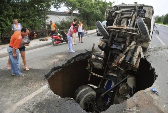 Mọi người nhìn một chiếc xe chở xăng bị rơi xuống hố tử thần trên đường phố ở tình Tây An thuộc tỉnh Thiểm Tây, Trung Quốc.