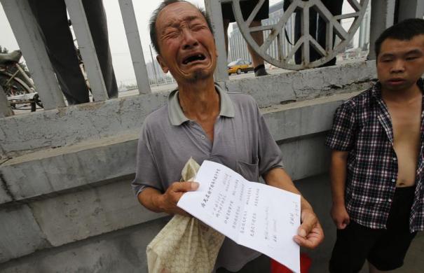 Một người đàn ông bật khóc khi đưa tờ đơn khiếu nại cho các phóng viên hãng tin Reuters ở gần Văn phòng tiếp nhận đơn khiếu nại ở Bắc Kinh, Trung Quốc.