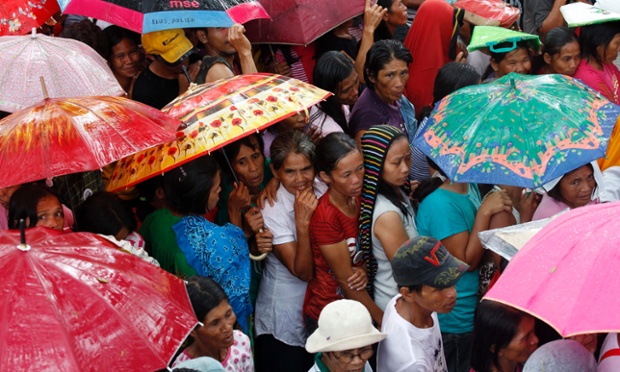 Những nạn nhân bị ảnh hưởng bởi động đất đứng xếp hàng đứng chờ nhận thực phẩm dưới mưa tại thị trấn Sagbayan, Philippines.
