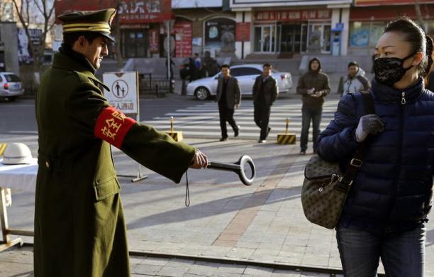 Người đi đường phàn ứng khi một nhân viên an ninh cầm thiết bị dò kim loại trên đường phố ở Urumqi, khu tự trị Tân Cương, Trung Quốc.