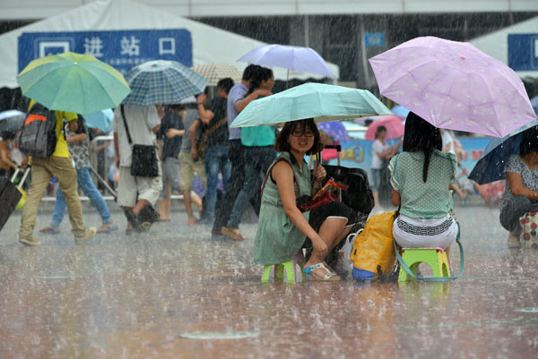 Hành khách ngồi dưới mưa để chờ lấy lại tiền vé tàu bên ngoài nhà ga Quảng Châu, sau khi lở đất khiến làm tê liệt tuyến đường sắt Quảng Châu, Trung Quốc.