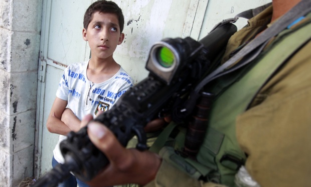 Một cậu bé người Palestin ngước nhìn binh sĩ Israel, sau khi cậu bé bị bắt giữ trong một cuộc biểu tình ở thành phố Hebron, Bờ Tây.