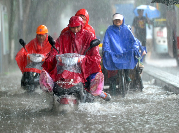 Mọi người đi xe máy qua đường phố ngập nước dưới mưa lớn ở Nam Kinh, Giang Tô, Trung Quốc.