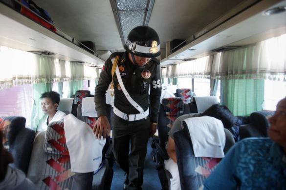 Lực lượng an ninh kiểm tra một chiếc xe bus và hành khách di chuyển vào thủ đô Phnom Penh, Campuchia.