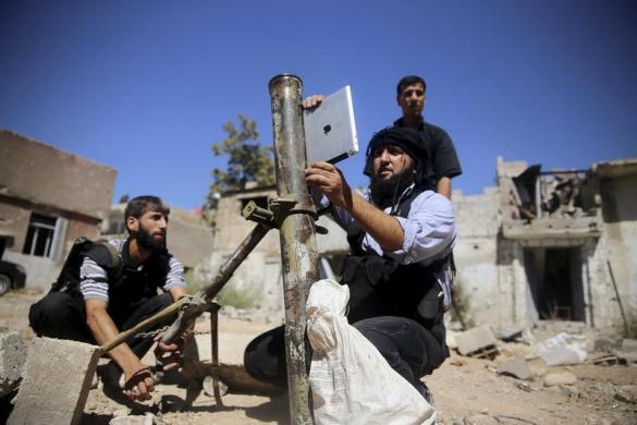 Một chiến binh phiến quân Syria sử dụng iPad, trong khi chuẩn bị bắn đạn cối tự chế ở Jobar, Damascus.