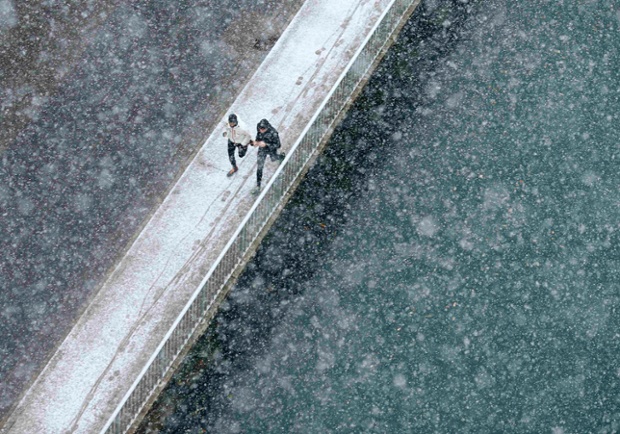 Hai người chạy bộ dọc bờ kè sông Aare dưới mưa tuyết đầu mùa ở Bern, Thụy Sĩ.
