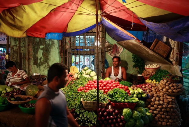 Người bán rau quả chờ khách tới mua tại một khu chợ ở Mumbai, Ấn Độ.