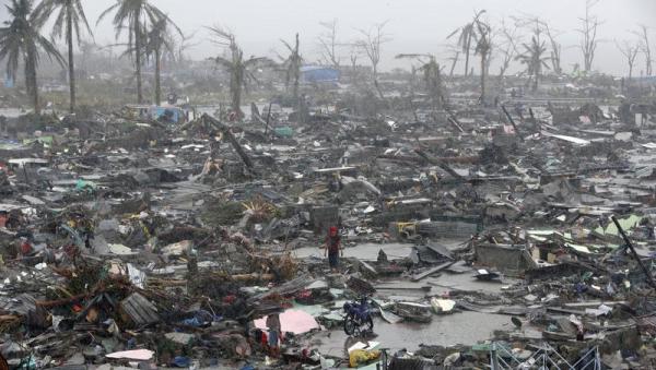 Những người sống sót đứng giữa đống đổ nát của các ngôi nhà bị phá hủy sau siêu bão Haiyan ở thành phố Tacloban, Philippines.