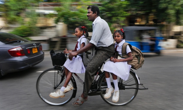 Một người đàn ông đạp xe đưa hai cô con gái tới trường vào buổi sáng ở Colombo, Sri Lanka.