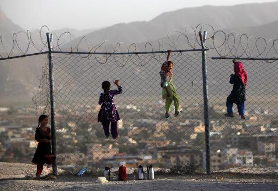 Các bé gái trèo lên hàng rào dây theo khi chúng bán trà dạo ở Kabul, Afghanistan.