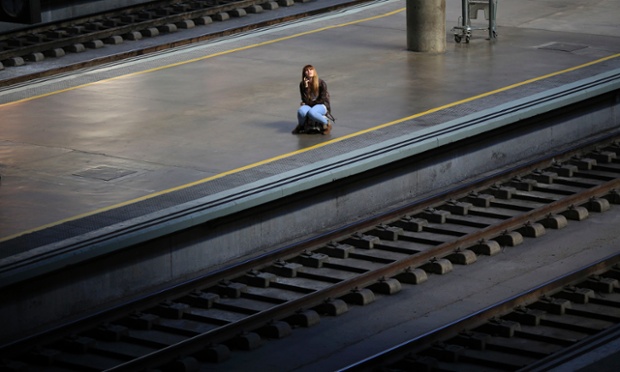 Một phụ nữ ngồi trên vali tại nhà ga không một bóng người ở Seville, Tây Ban Nha, khi nhân viên đường sắt nước này tổ chức đình công trên toàn quốc.