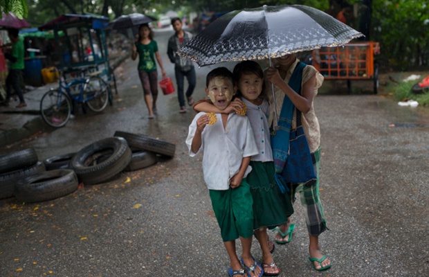 Trẻ em ăn kẹo trong khi đi học dưới trời mưa ở Rangoon, Myanmar.