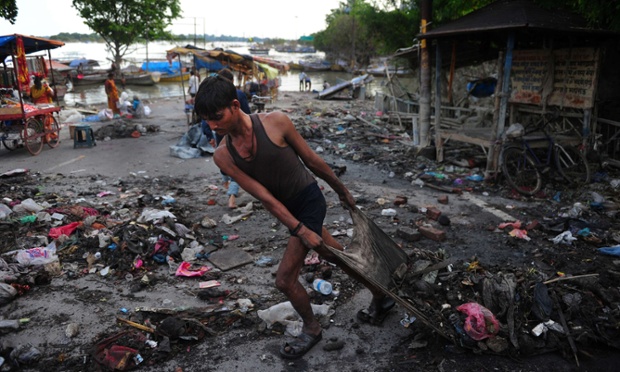 Một người đàn ông dọn rác trên bờ sông Hằng sau khi nước lũ rút xuống ở Allahabad, Ấn Độ.