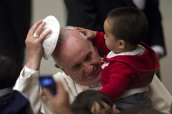 Một em bé xoa đầu Giáo hoàng Francis trước bài phát biểu của ông tại hội trường Paul VI, Vatican.