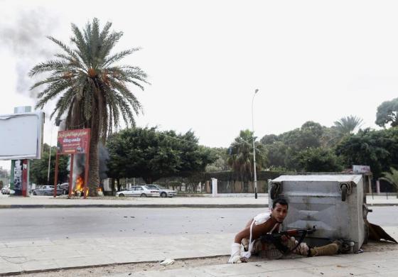 Một thành viên của quân đội Libya trú sau thủng rác trong khi chiến đấu với phần tử Hồi giáo vũ trang ở Benghazi.