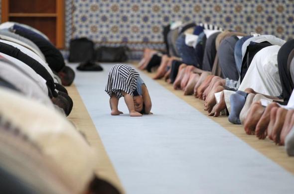 Một em bé chơi gần những tin đồ Hồi giáo đang cầu nguyện tại nhà thờ Strasbourg ở vùng Alsace của Pháp, trong ngày đầu tiên của tháng lễ Ramadan.