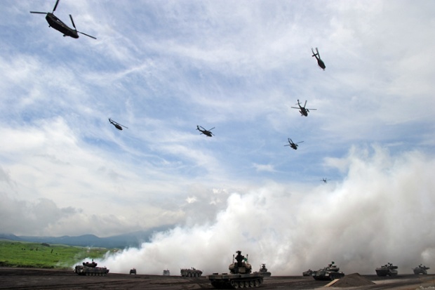 Máy bay trực thăng bay trên các phương tiện bọc thép trong cuộc tập trận bắn đạn thật của Lực lượng phòng vệ mặt đất Nhật Bản.