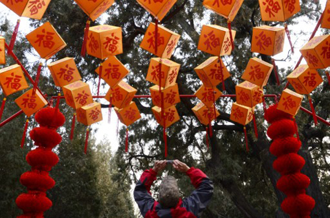 Bên trong một công viên ở Bắc Kinh, người đàn ông này chụp ảnh những chiếc đèn lồng đỏ v à in chữ "Phúc". Thành phố được trang hoàng lộng lẫy để đón ngày lễ lớn nhất trong năm.