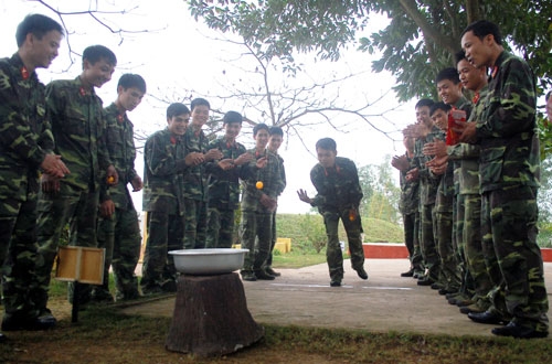 Chiến sĩ trẻ Lữ đoàn 241 chơi trò chơi ném bóng bàn vào chậu. 