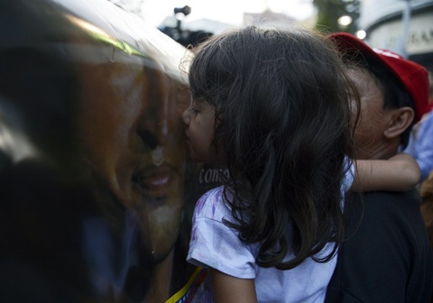 Bé gái hôn ảnh cố tổng thống Hugo Chavez. Ảnh: AFP