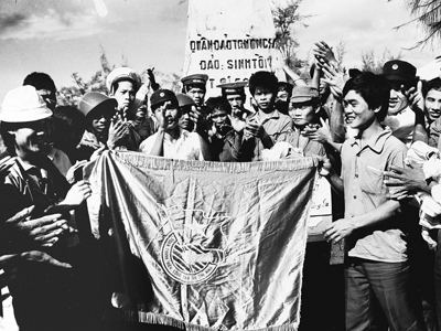 Tháng 3/1988, nhận nhiệm vụ của T.Ư Đoàn TNCS Hồ Chí Minh, PV Báo Tiền Phong (bìa trái) trao cờ Đoàn cho chiến sĩ trẻ trên đảo Sinh Tồn. Ảnh: Đình Trân