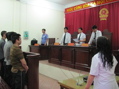 
	Các bị cáo (bìa trái) đứng nghe tòa tuyên án.