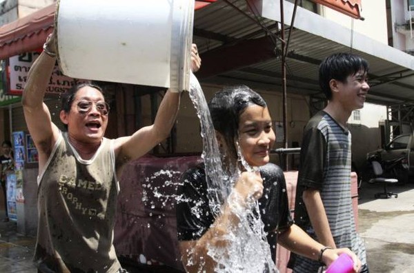 Một người đàn ông đổ sô nước lên cô gái đang đi trên đường phố ở Bangkok.