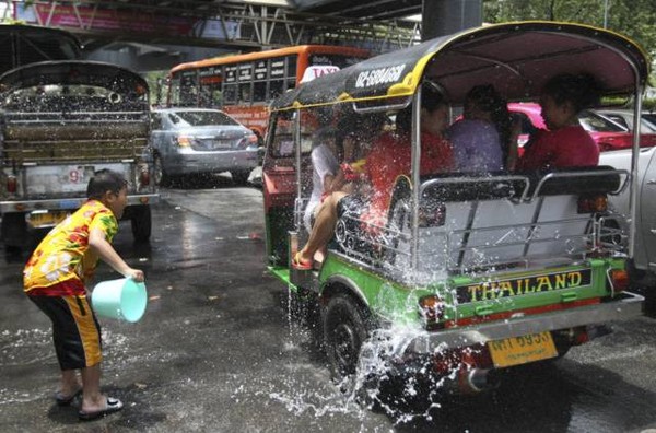 Những vị khách trên xe tuk tuk bị một cậu bé té nước khi đang tham quan Bangkok.