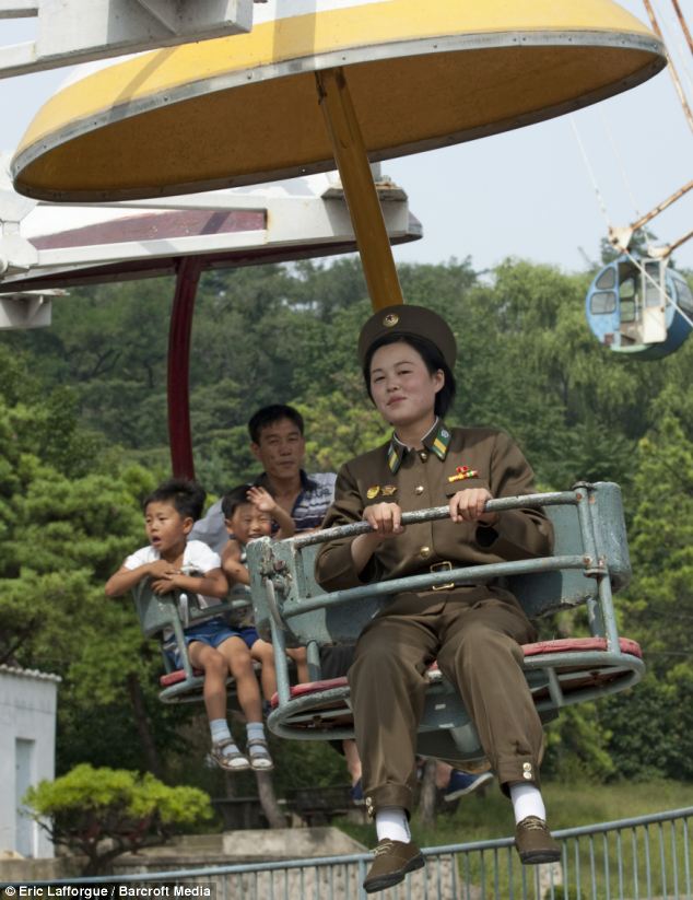 Chilling at the fair: This young soldier shows an entirely different side to North Korea as she enjoys her ride on a rollercoaster