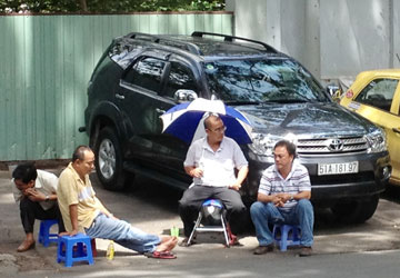 
	Người đàn ông tên Điểu (che dù) đang điều hành việc “thu phí” trên đường Lê Văn Hưu.
